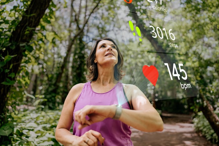 A person exercising outside checks the metrics on their smartwatch.