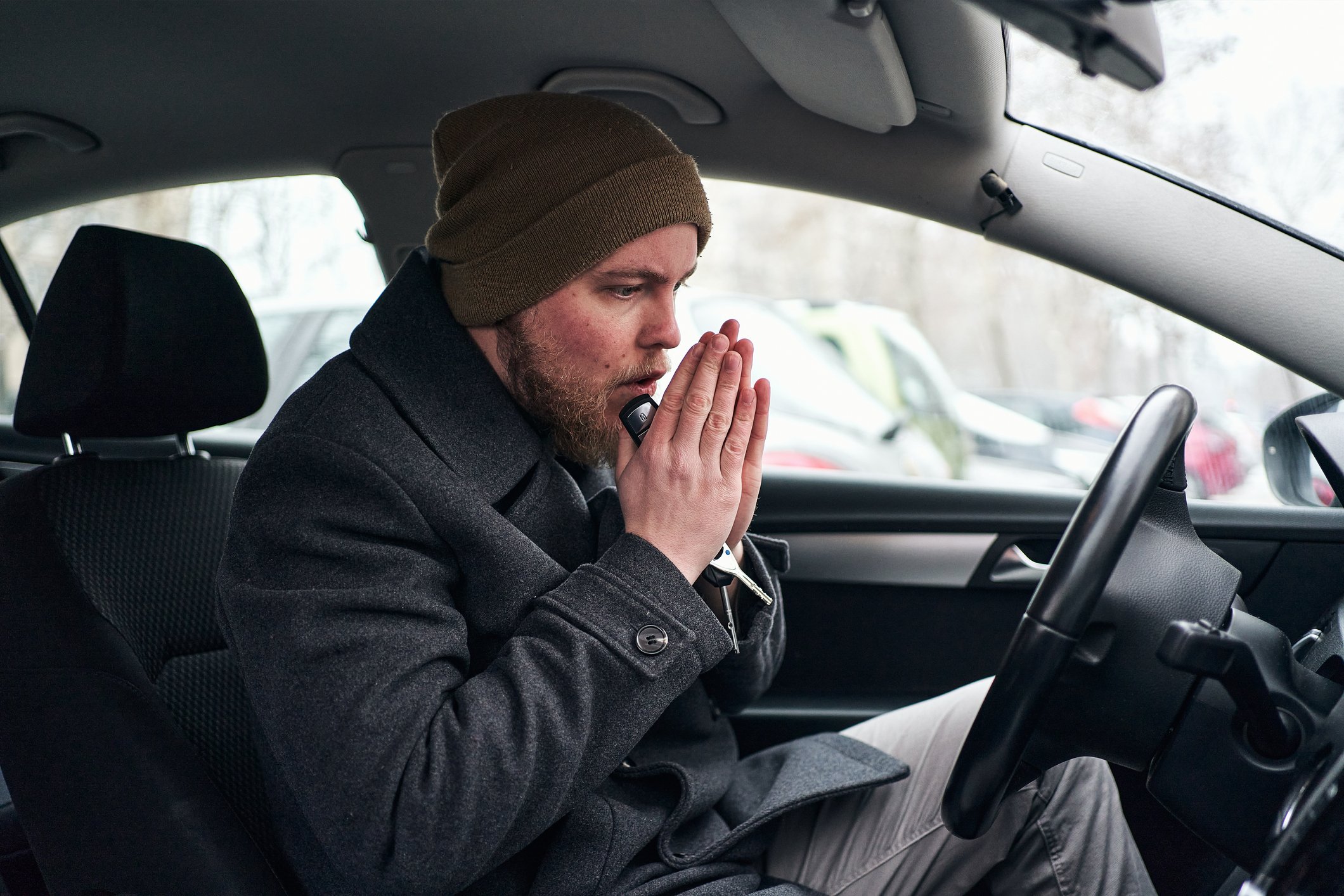 Person putting hands together in the drivers seat of a car