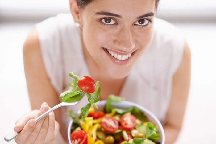 Person smiles with a salad.