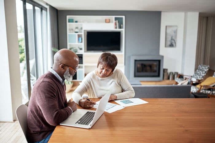Couple looking at documents together at dining table.