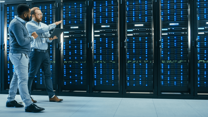 Two engineers walking along a row of servers in a data center.