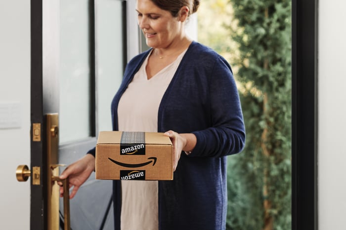 Customer holding Amazon delivery box in hand.