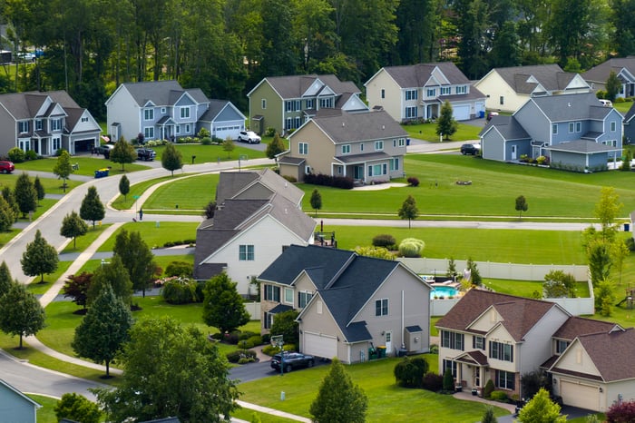 A photo of several houses in a new residential suburb, surrounded by lush greenery.