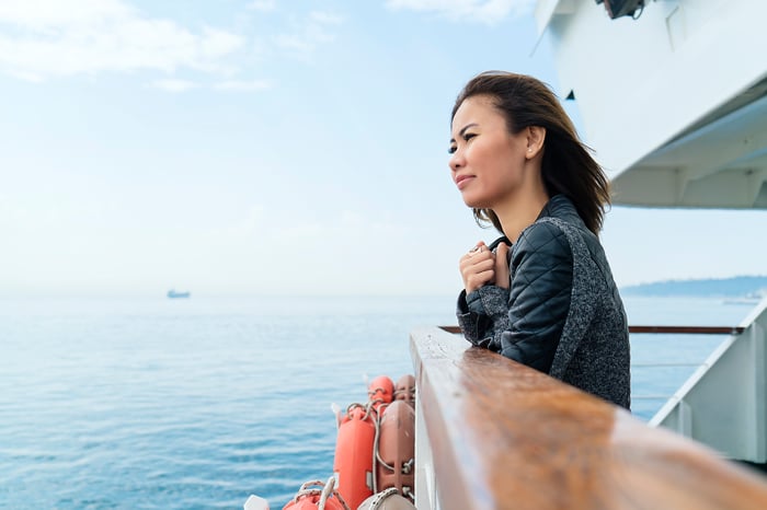 Person on ship's deck, looking out at ocean.