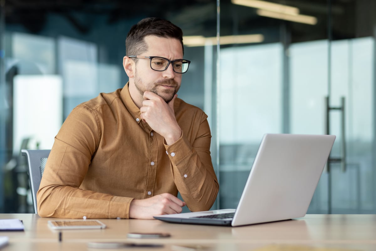 An investor looking at a laptop computer with a concerned expression.