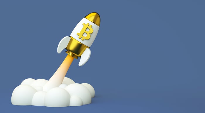 A toy spaceship with the Bitcoin logo launching.