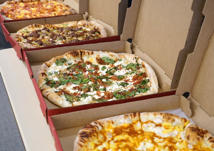 Row of pizzas in delivery boxes.