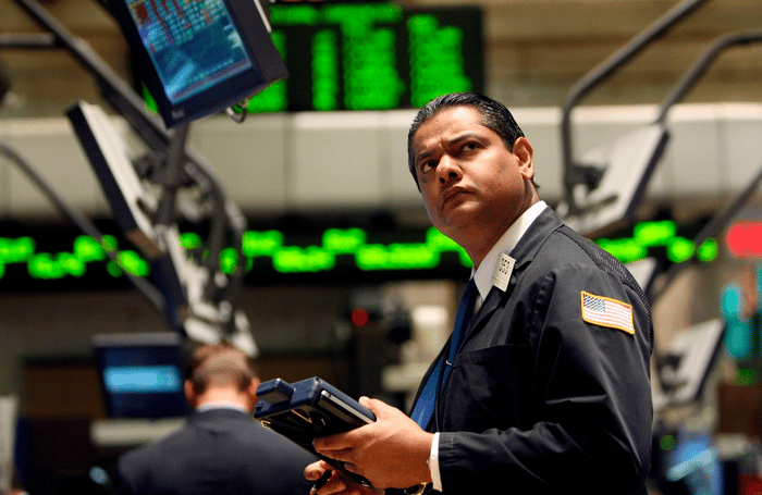 A New York Stock Exchange floor trader looking up in bewilderment at a computer monitor.