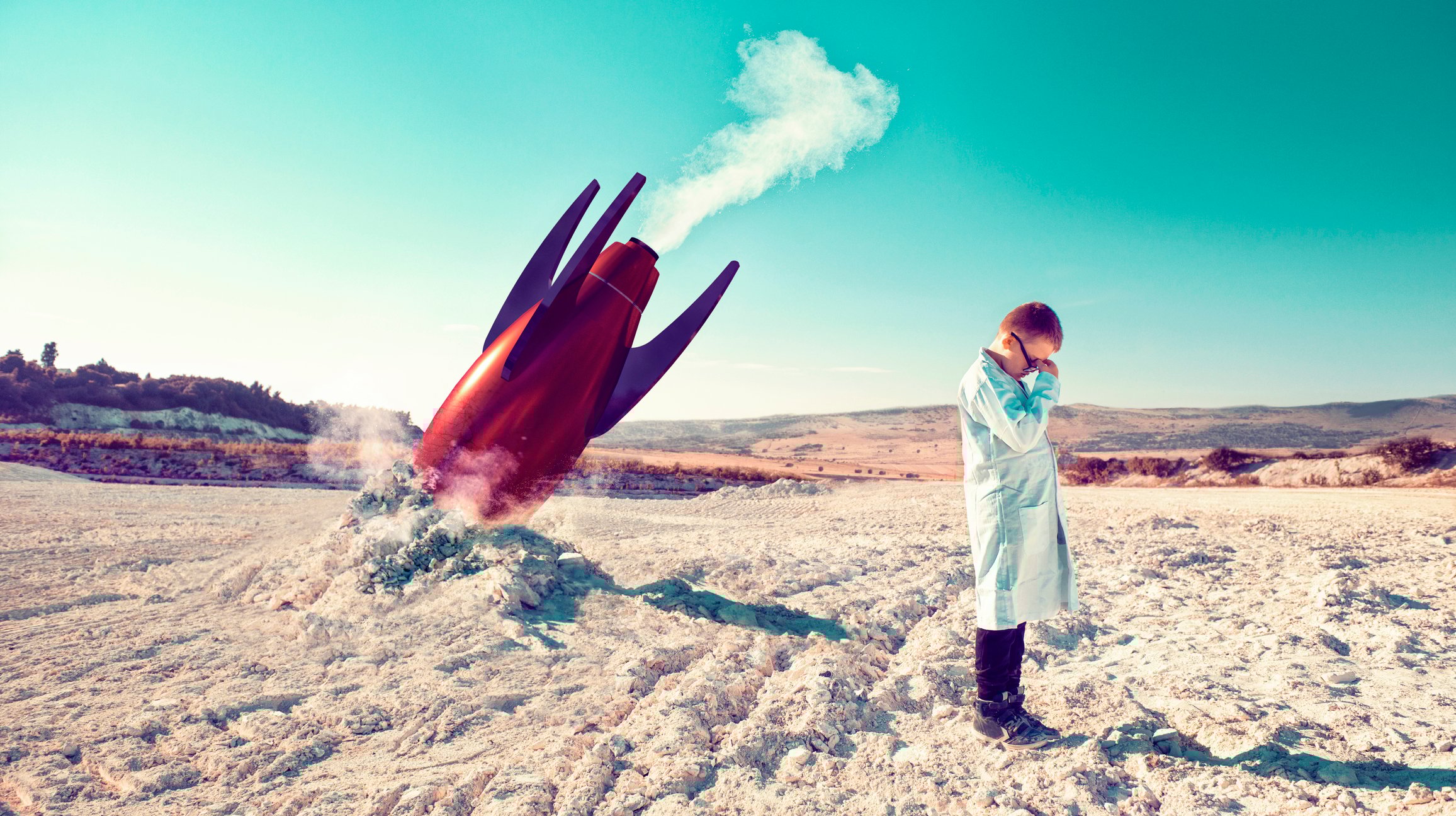 Boy in a lab coat is crying next to a crashed rocket.