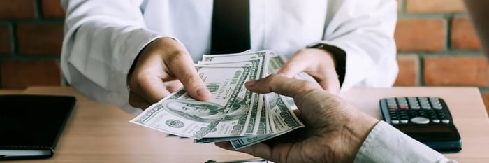 A person handing cash to another person.