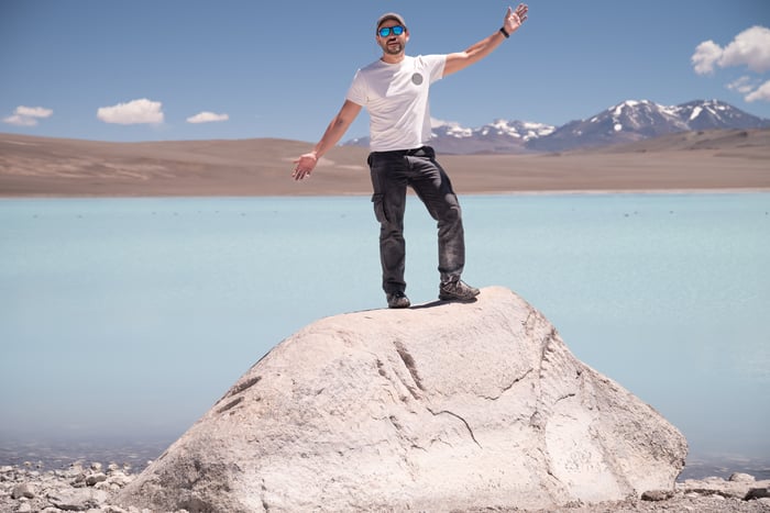 Man stands on top of mound of lithium sand. 
