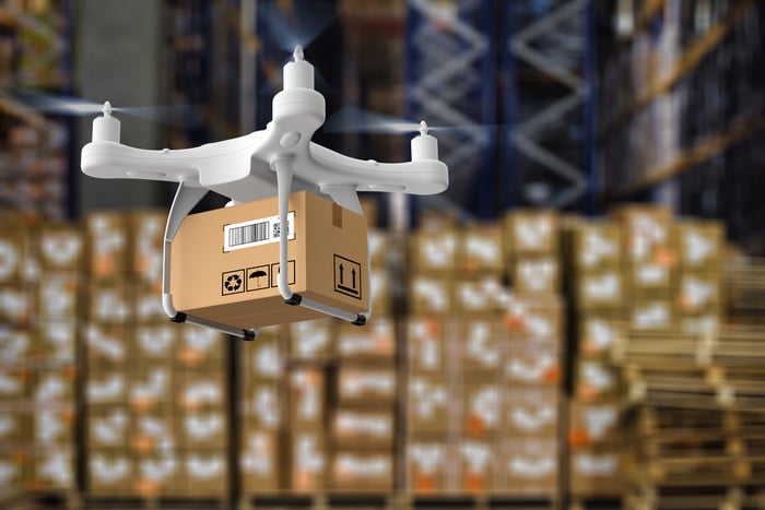 A drone handles a package in a warehouse.