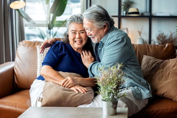 A couple is smiling on a couch.