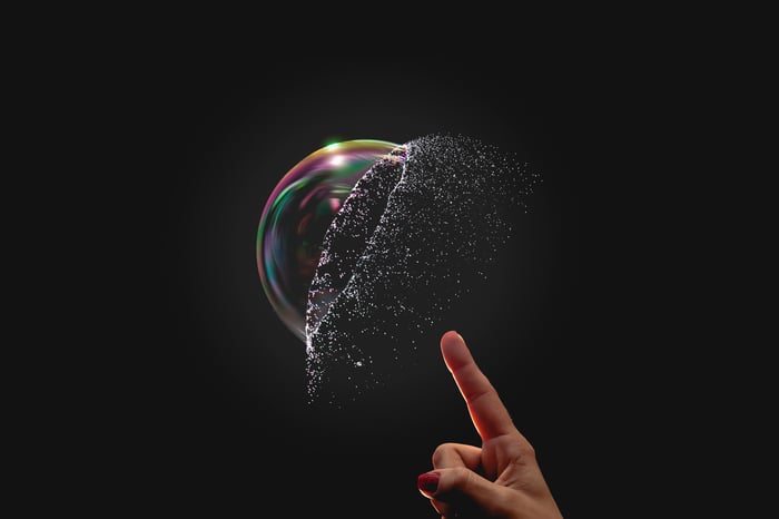 A finger pointing to a bubble popping.
