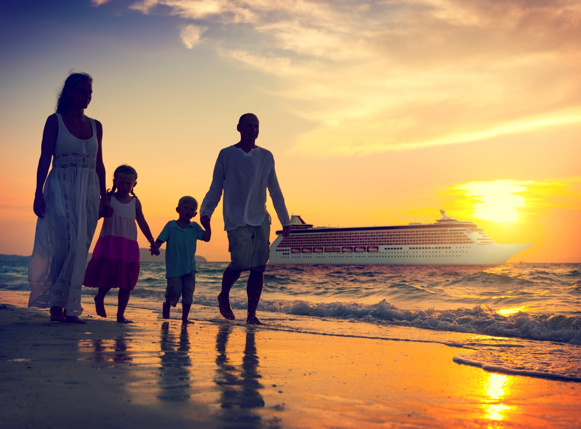 People walking on a beach with a cruise ship in the background.