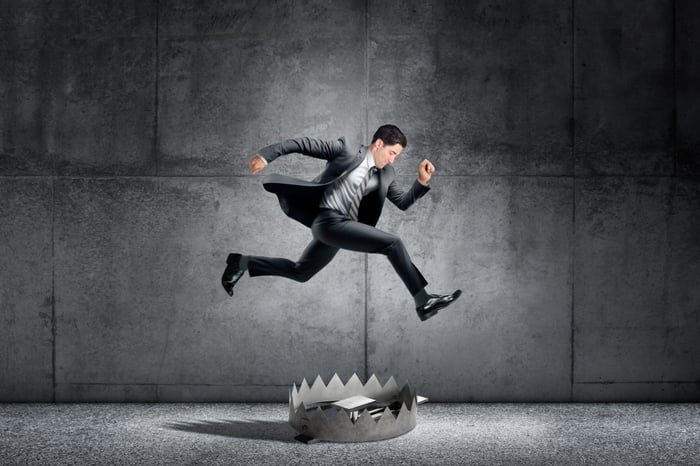 A person in a suit jumps over a bear trap.