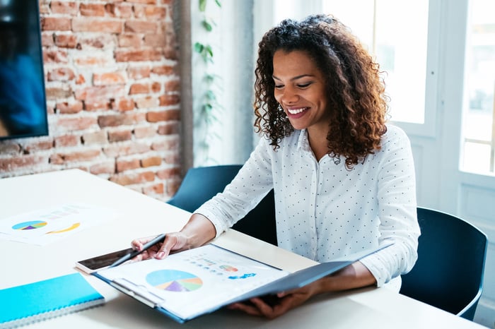 A business person smiles while reviewing charts and graphs.