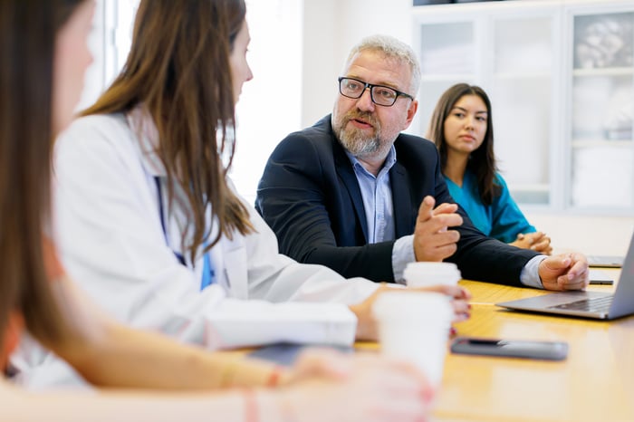 Businessperson talking to colleagues in a meeting.