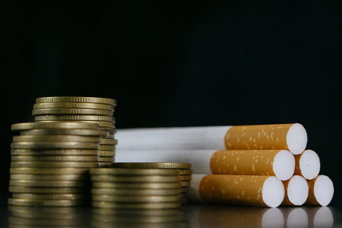 Six cigarettes beside stacked-up coins.