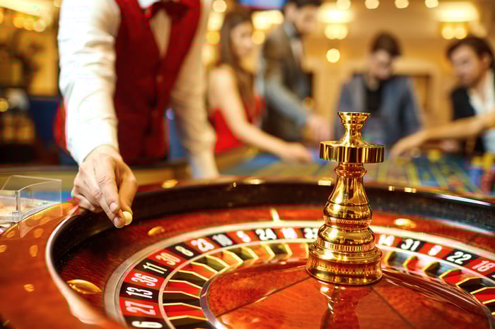 A casino dealer placing a ball on a roulette wheel.