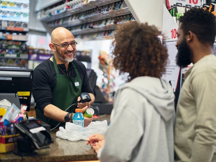 A couple shopping at a store, checking out with a cashier.