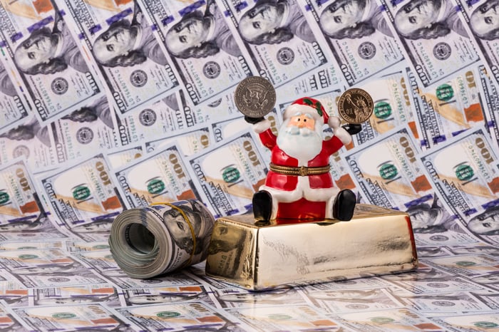 A Santa Claus figure in front of money and a gold bar