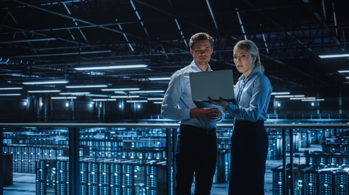Technicians look at a laptop inside an AI data center.