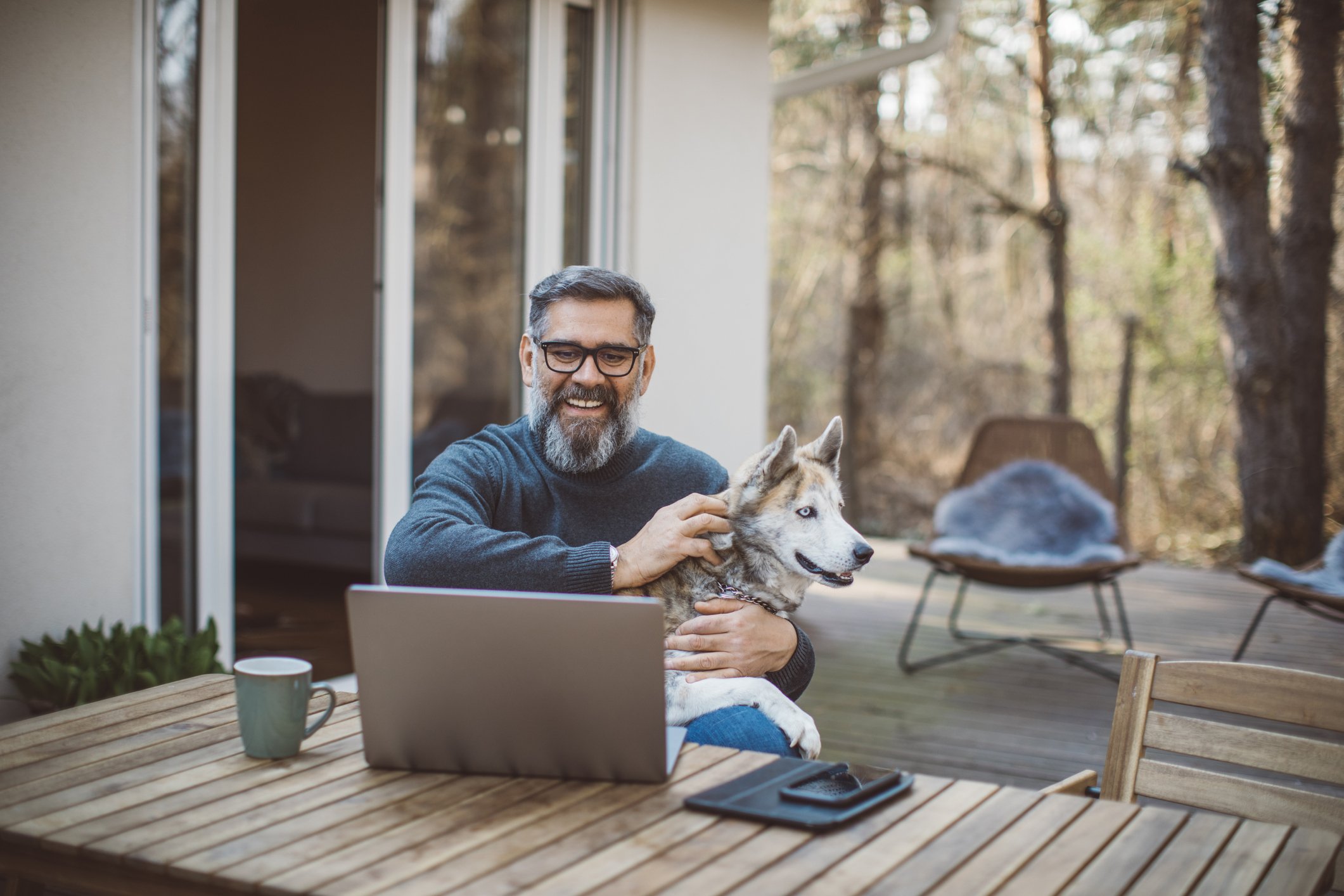 Older man at laptop with dog_GettyImages-1214136074