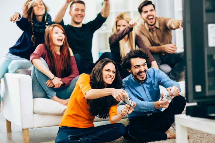 Friends cheering on two video game players.