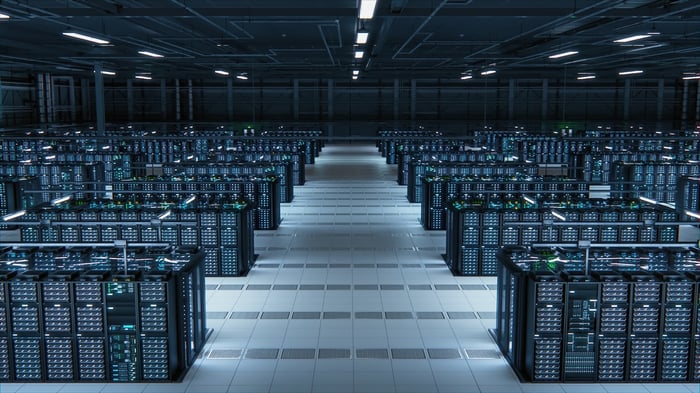 A wide corridor dividing servers in a data center room.
