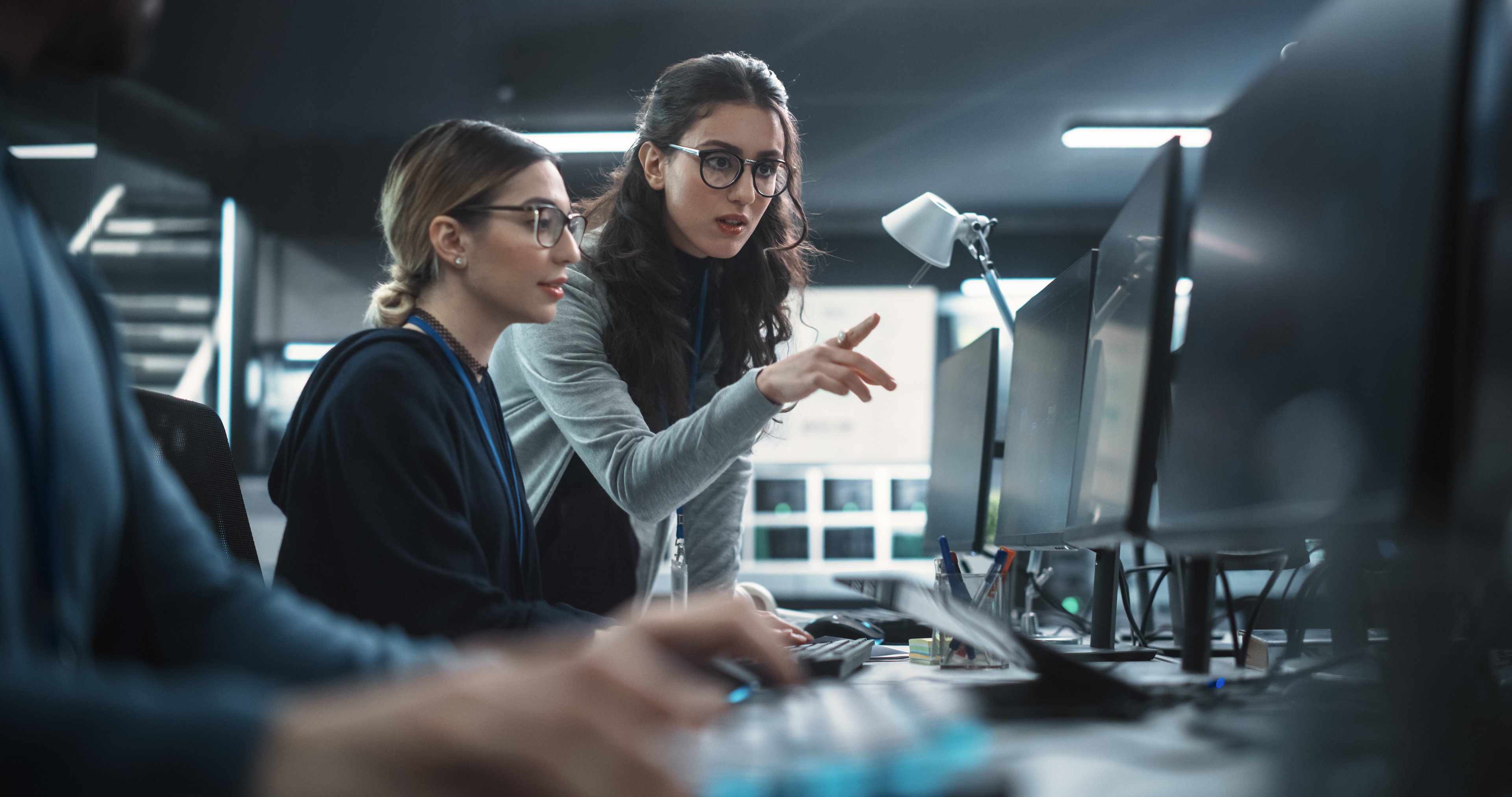 Two cybersecurity managers looking at a computer monitor and talking to each other
