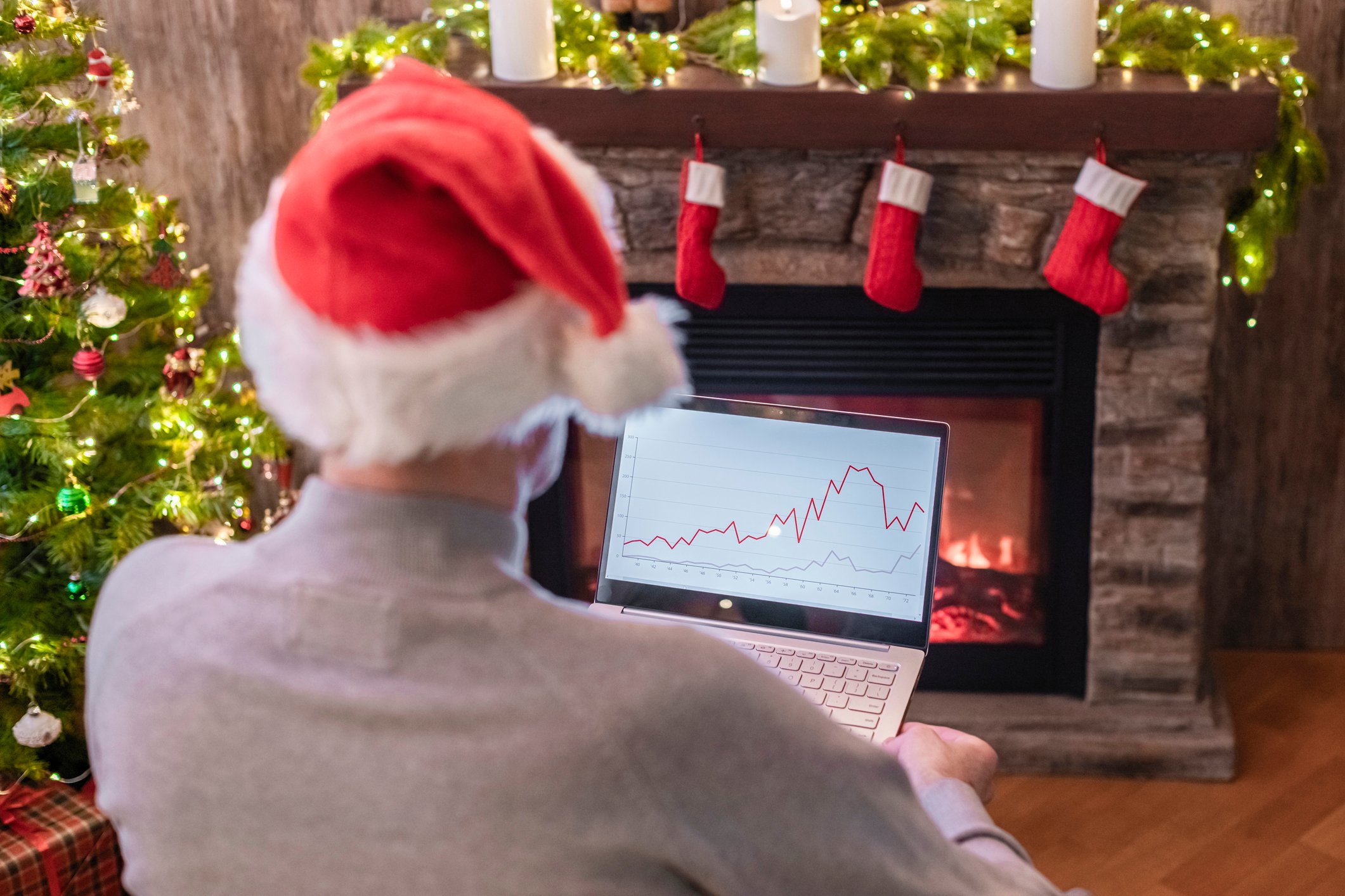 holiday person on laptop stock market in front of fireplace
