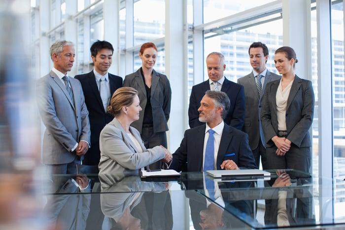 Businesspeople shaking hands in conference room.