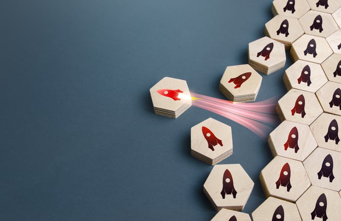 A bunch of wooden-tile hexagons with a rocket are lined up on the right side of the picture, with one rocket tile turned sideways and blasting off to break away from the group.