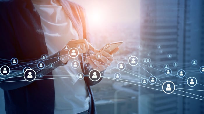 smartphone user typing with symbols for other social networking site users floating around.