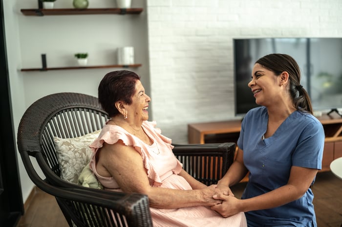 A healthcare worker holding a patient's hands.