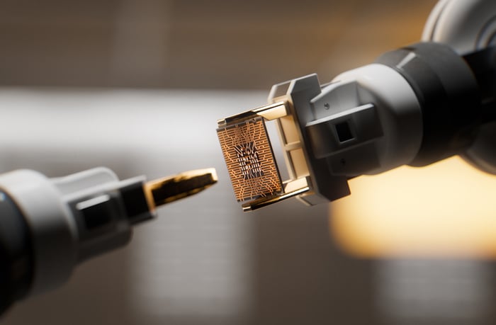 A semiconductor being positioned for assembly by a robotic arm.