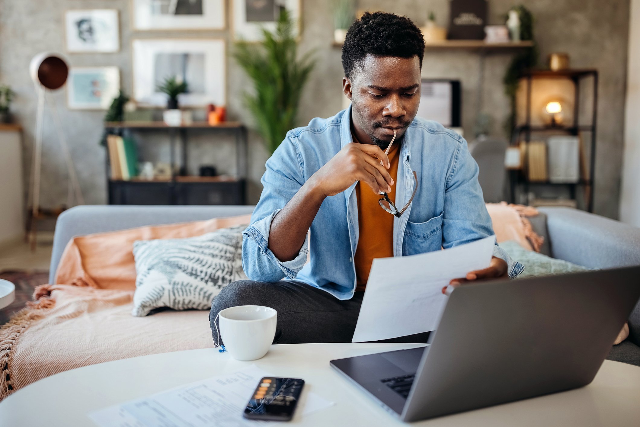 person sitting at home looking at documents and a laptop
