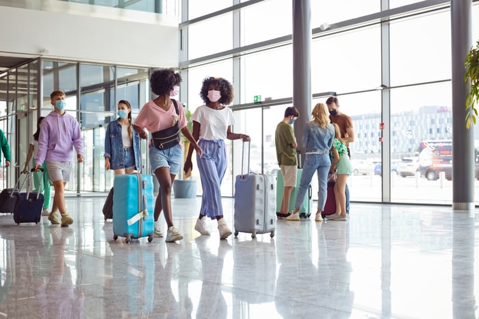 Two travelers moving through an airport corridor.