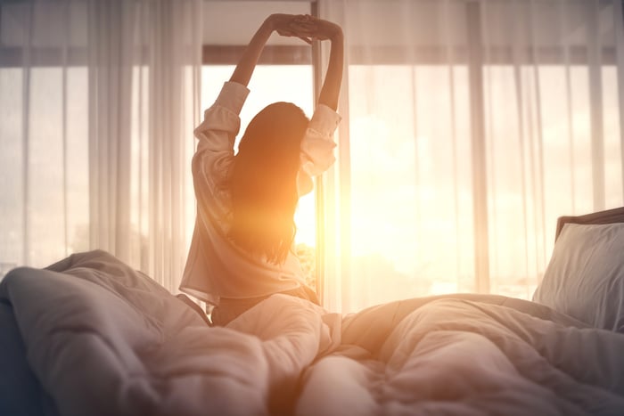 Person in bed arising and stretching in the morning.