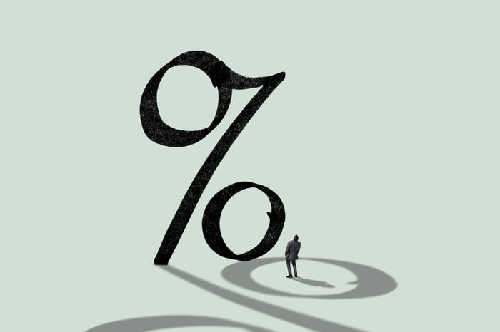 A person looking up at a large percent sign.