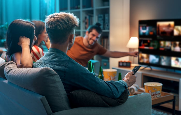 A group of young adults watching TV together at home.