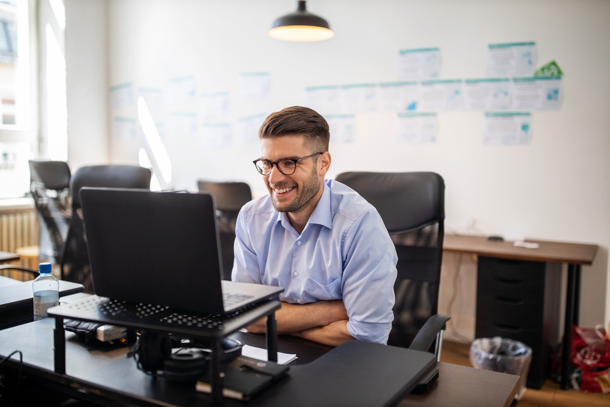 business person sitting in office smiling and looking at computer screen