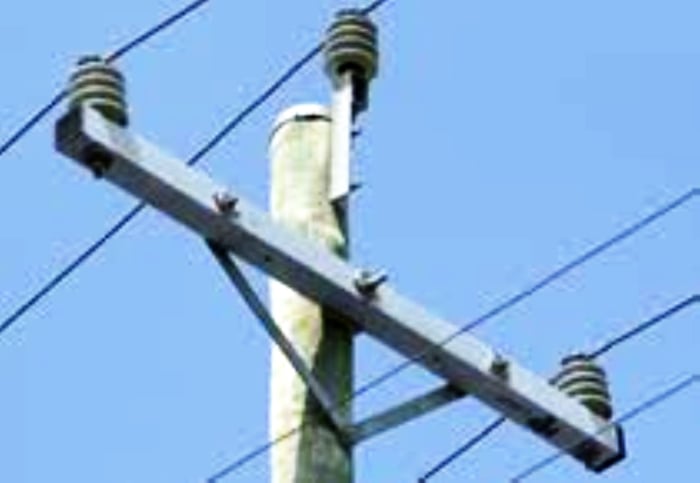Upper part of an electric transmission utility pole showing wires and various hardware.