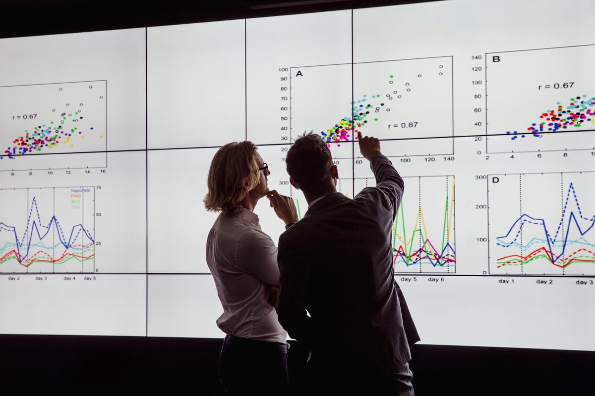24_08_20 Two people looking at a giant screen with graphs on it _MF Dload GettyImages-872019580-1201x800-5b2df79