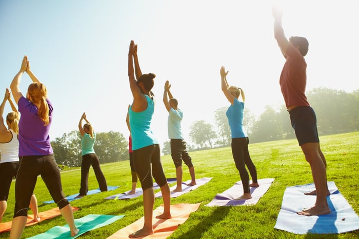 A group of people in yoga pants, doing yoga in a park.