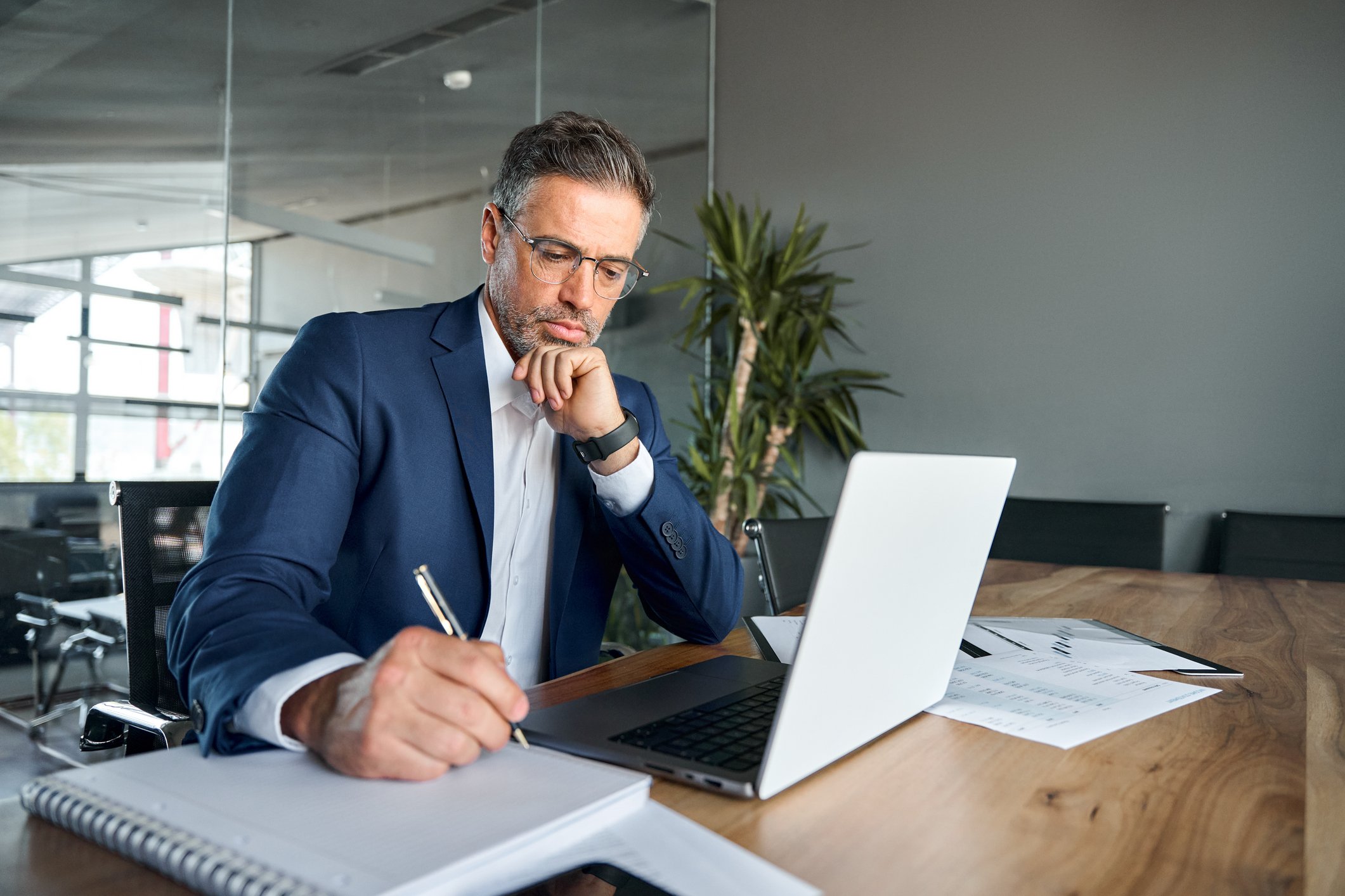 man 40s biz suit desk taking notes GettyImages-1552851631
