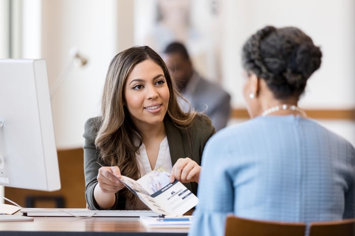 An advisor holding a pamphlet and explaining options to a client.