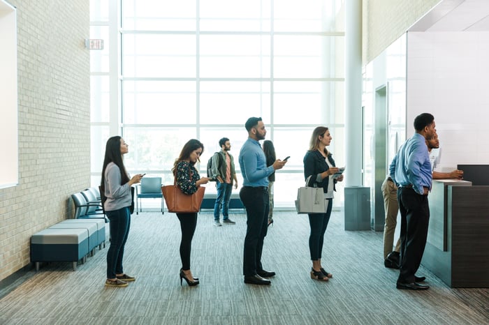 People standing in line inside a bank.
