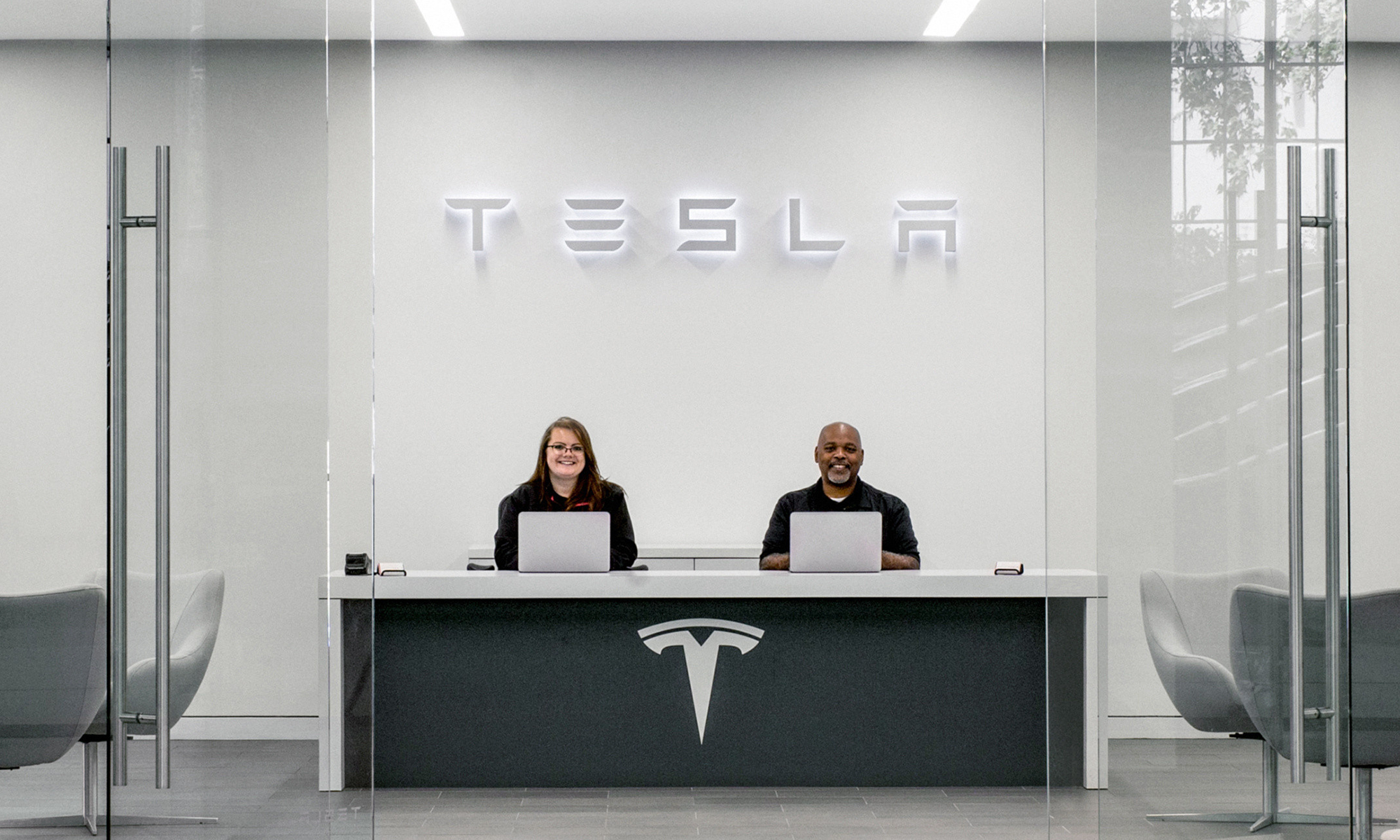 tesla service center with two associates at desk with tesla logo (1)